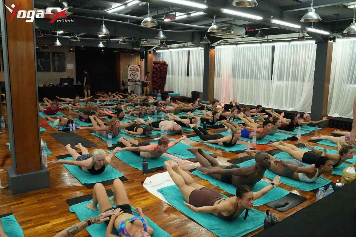 Full Bikram yoga class in session at YogaFX Bali showing students in standing series in natural 40-degree tropical heat