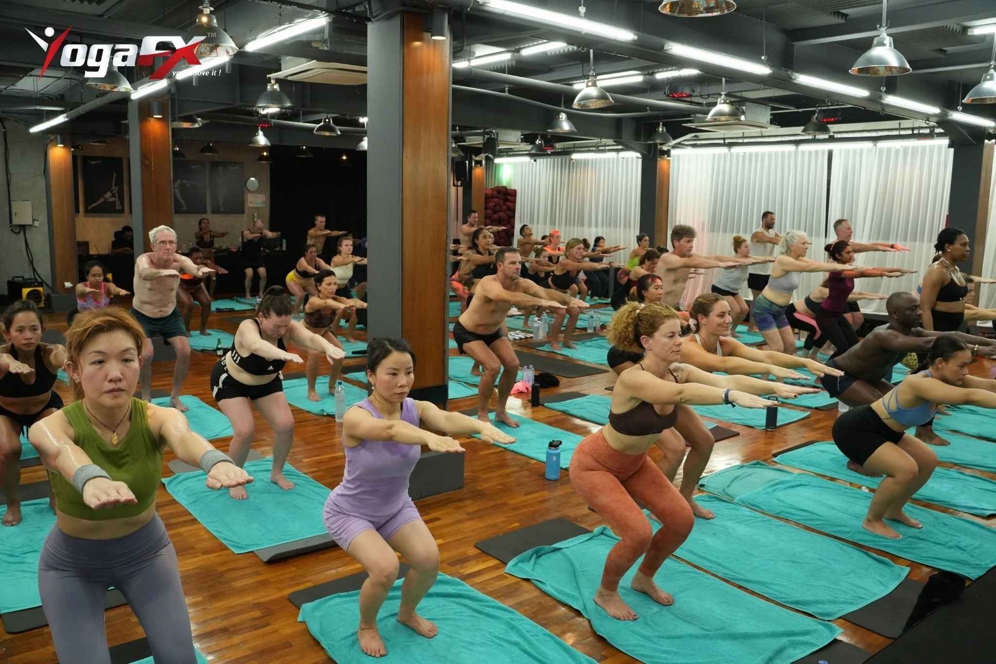 Bikram yoga teacher trainees practising the 26&2 sequence in natural tropical heat during a YogaFX teacher training intensive in Bali