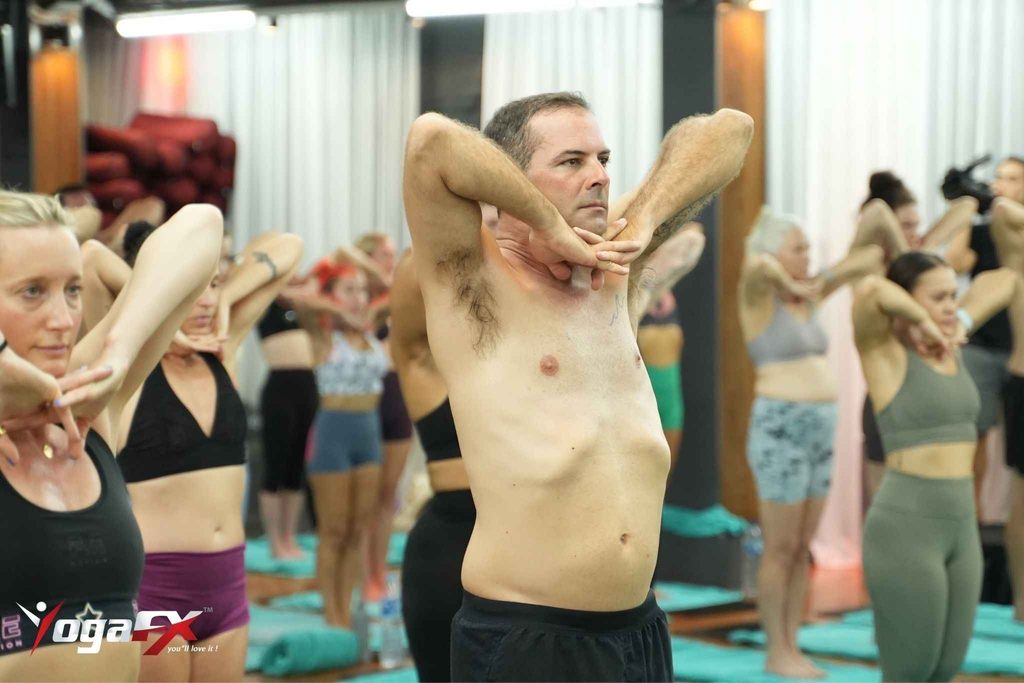Instructor giving individual dialogue and posture correction to a small capped cohort during Bikram yoga teacher training