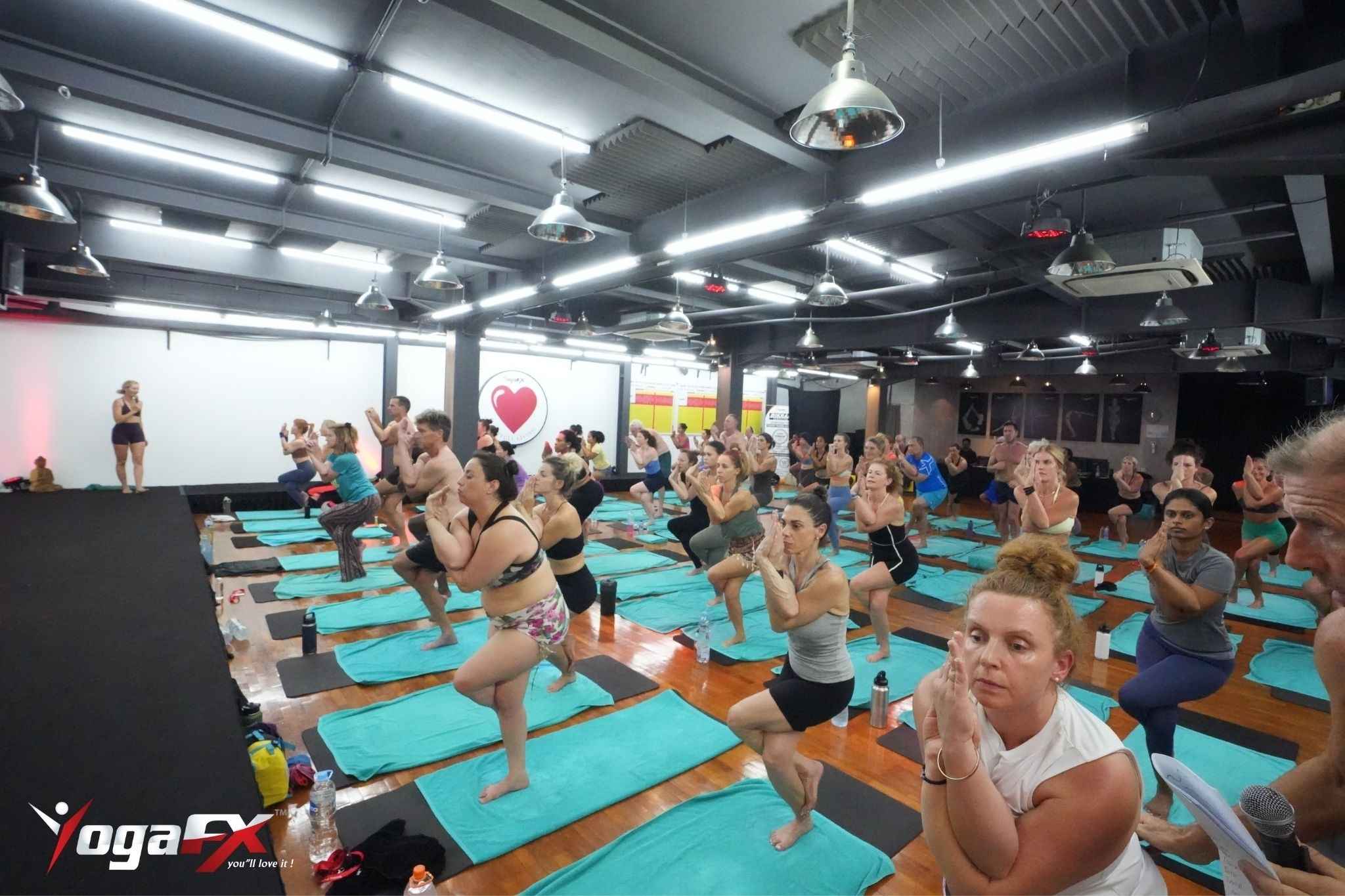 Practitioner in a forward fold posture during a heated yoga class, one of the postures linked to parasympathetic nervous system activation