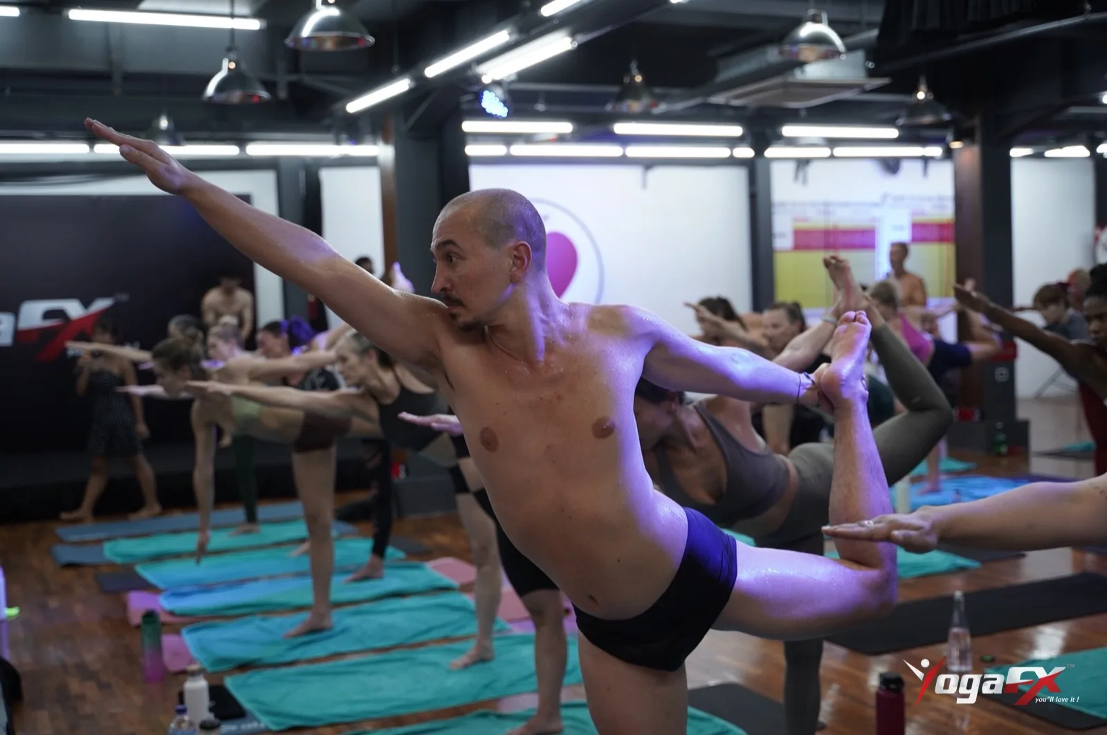 Trainees hold standing bow pulling pose in a Bali class, the kind of posture judged under international yoga sports federation rules